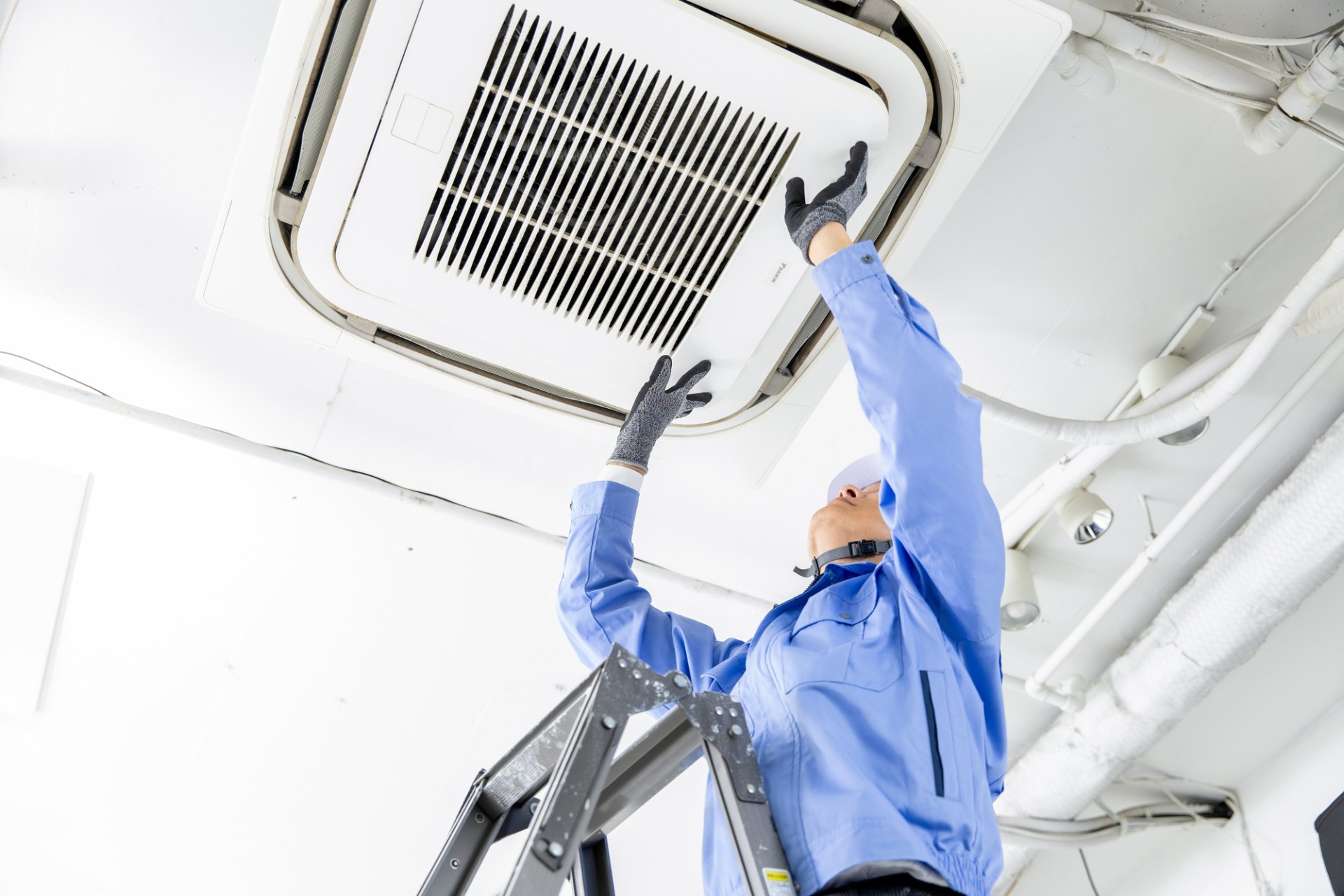A close-up photo of a restaurant ceiling cassette air conditioner opened up to check the heat exchanger and drain pan