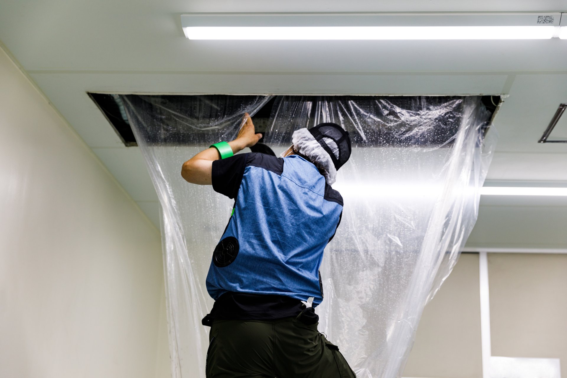 A workbench in a clinic treatment room with removed air conditioner parts laid out so the condition before and after cleaning can be compared